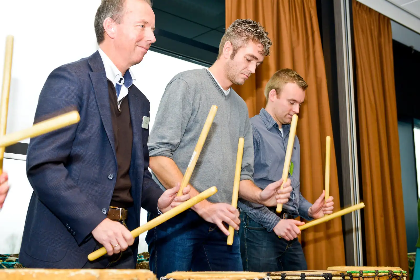 Mannen drummen op bastrommels tijdens een djembé workshop