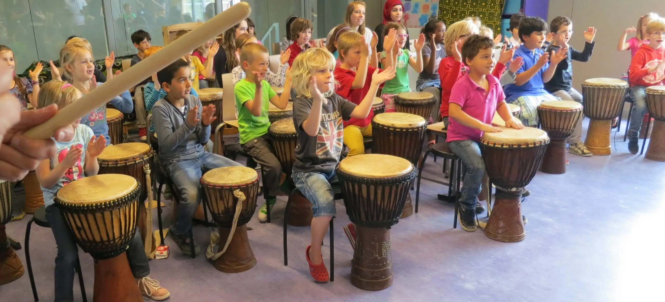 Kinderen spelen djembé tijdens een workshop op school